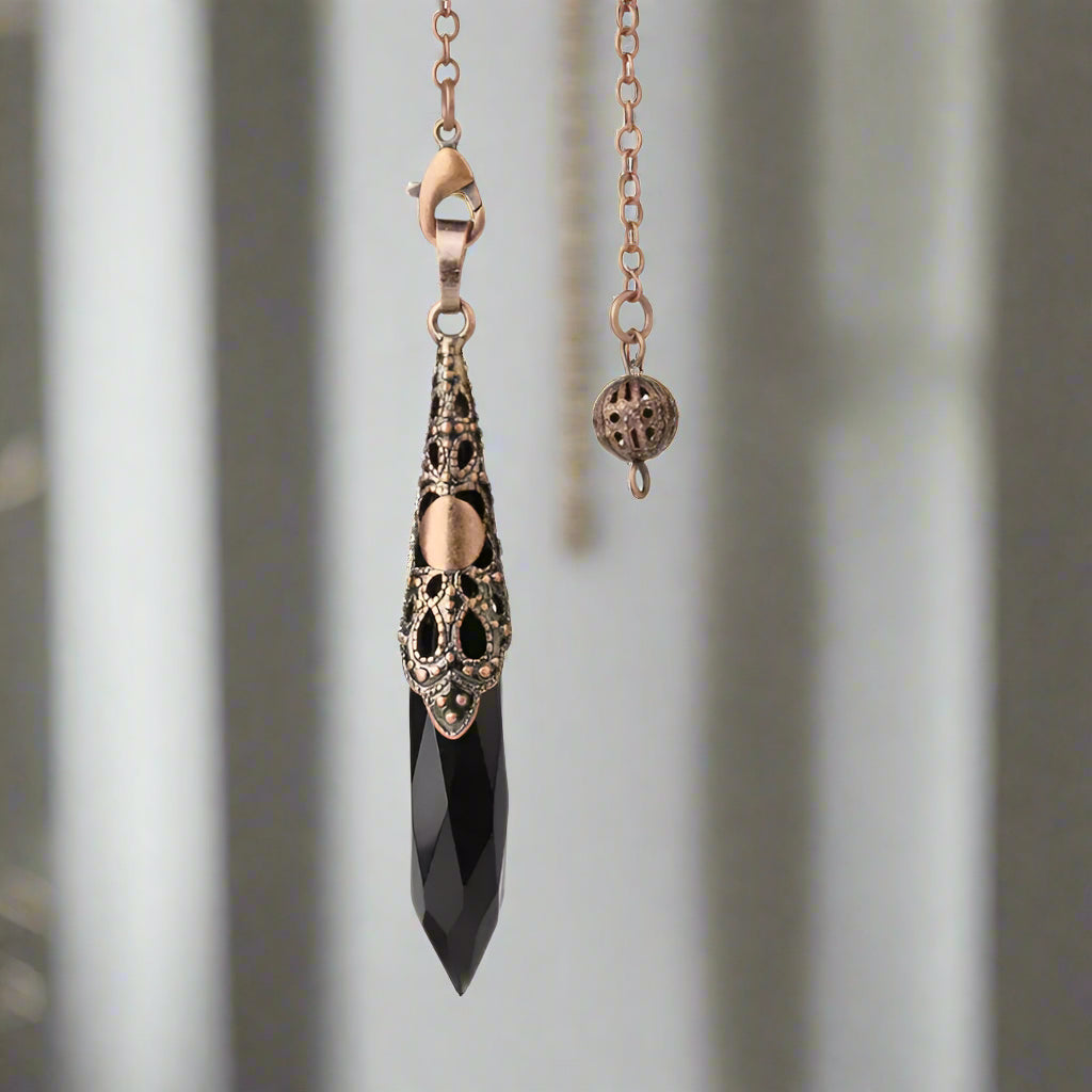 A Black Onyx pendulum with copper chain and decorative caps.