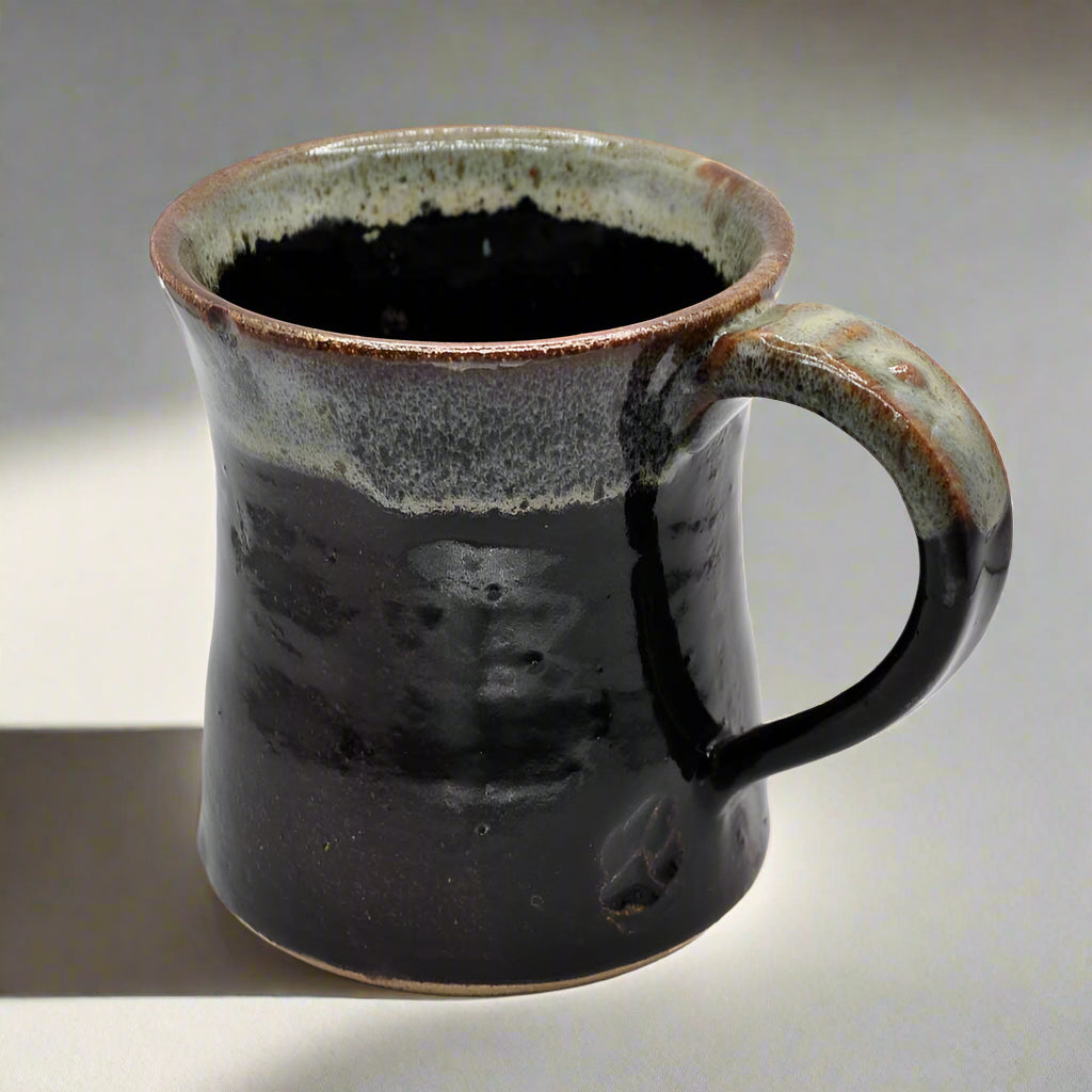 A ceramic mug with a dark brown color and a handle on the right side, displayed against a plain background.