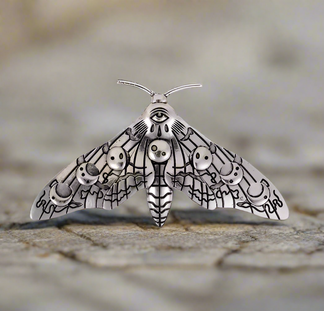 A hair clip designed as a moth with detailed black and white patterns on its wings.